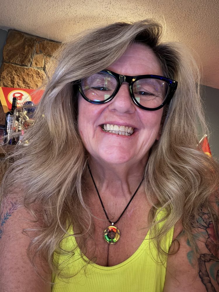Tish smiling in black glasses and a yellow tank top